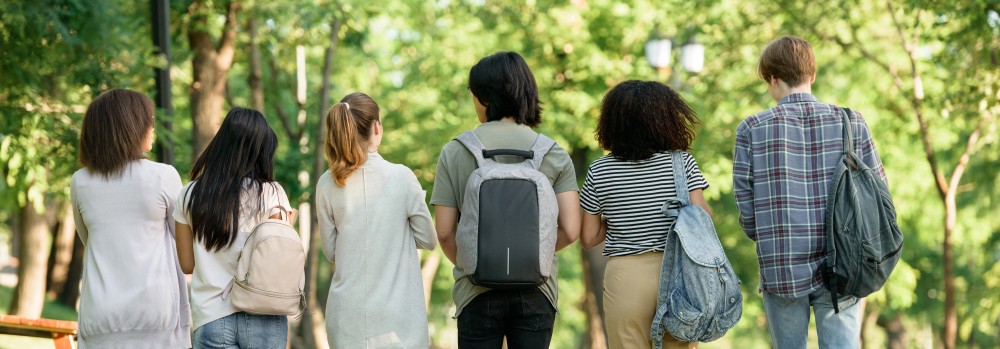 Eine Gruppe junger Studierenede läuft über einen Campus.